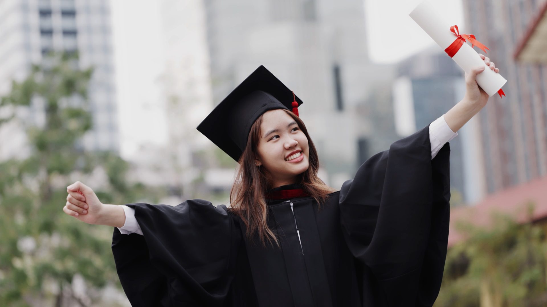 A graduate in cap and gown raising her diploma in joyful celebration